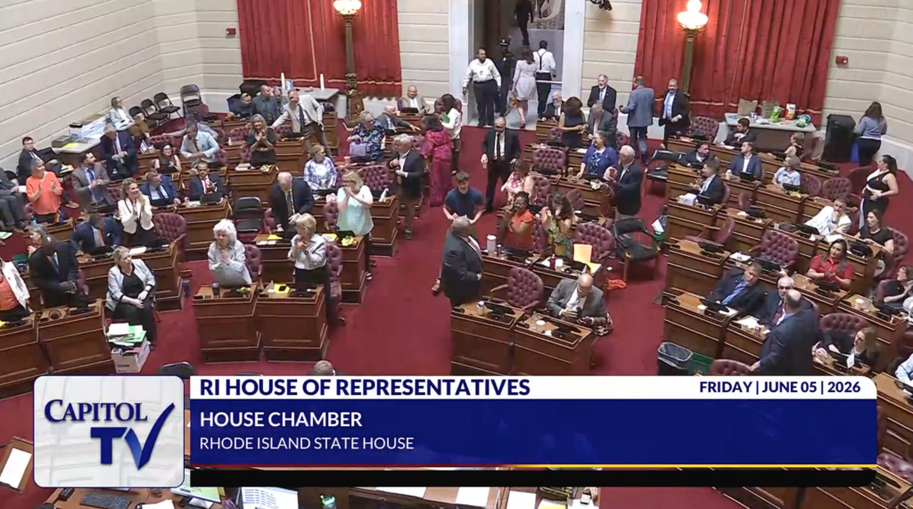 Capitol TV broadcast of the Rhode Island House of Representatives chamber on June 5, 2026. Representatives are seen standing, applauding, and mingling on the House floor following a vote.